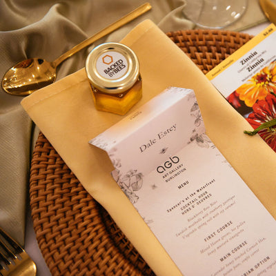 Table setting with a menu, honey jar, and decorative items on a woven placemat.