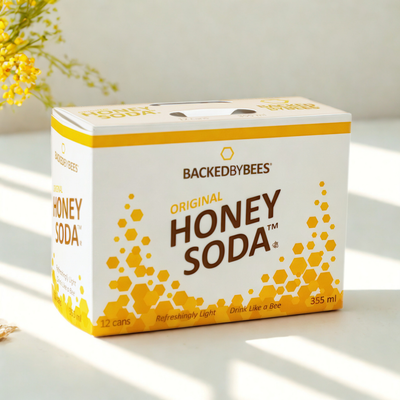 Box of BackedByBees Honey Soda on a light surface with a blurred background