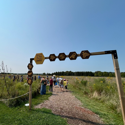 Pathway with directional signs in a field with people in the background