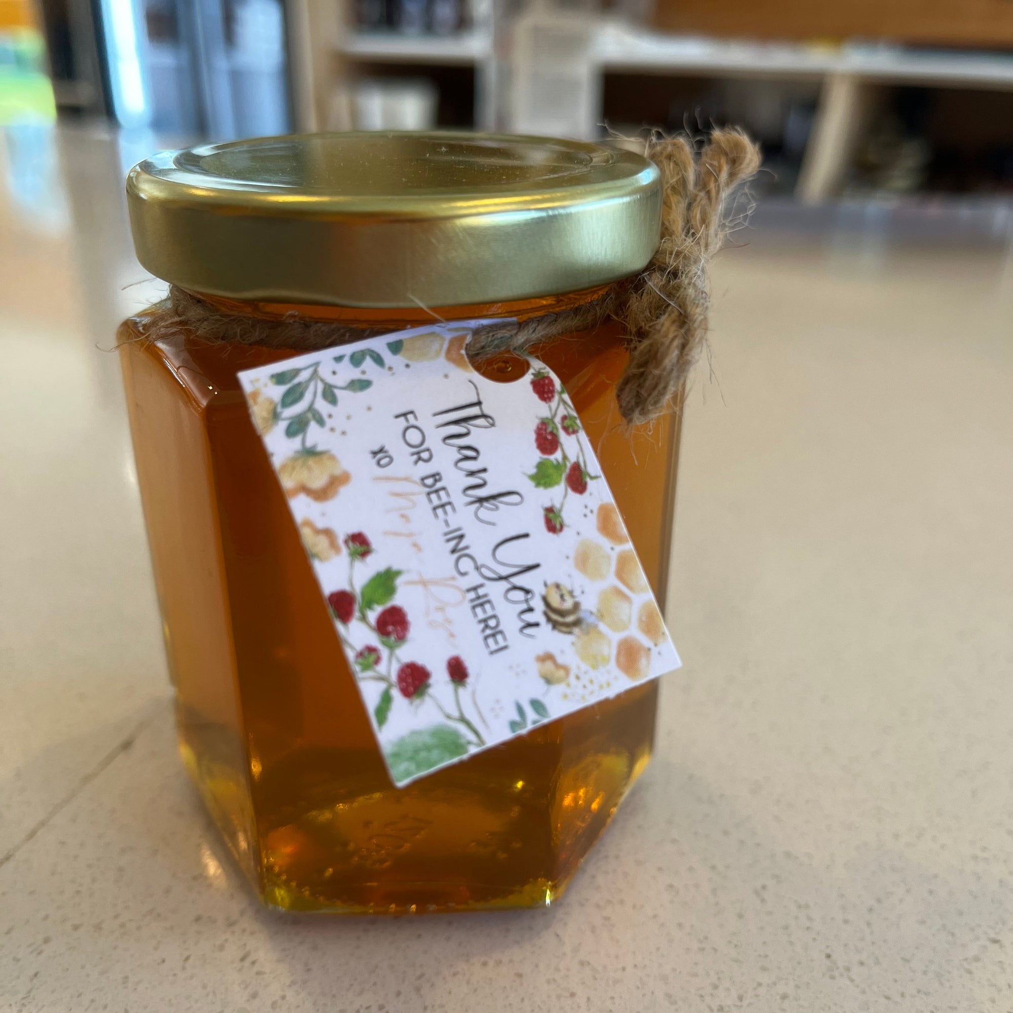 Jar of honey with a decorative label on a countertop